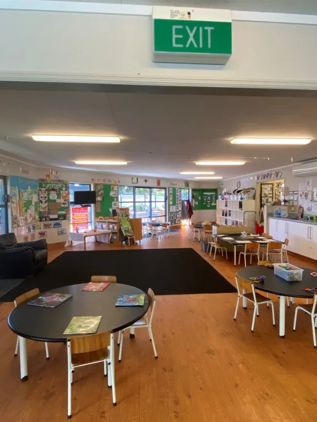 An open, light-filled preschool room with tables, natural resources and displays