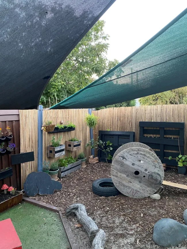 An outdoor loose parts area with tyres, cable reels and planting