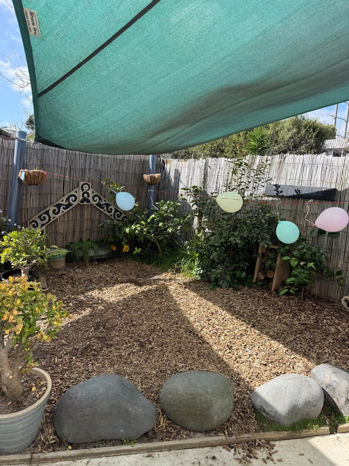 A shaded garden path with stones, plants and a bark trail in the preschool grounds